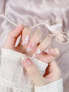 Detail of press-on nails with 3D white flower petals and pearls on gradient pink base