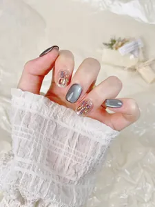 Détail de faux ongles œil-de-chat gris avec strass brillants et paillettes champagne