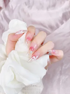 Detail of long ballerina fake nails with 3D white flowers, pearls and pink blush gradient