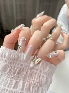 Detail of nude pink long ballerina nails with 3D butterfly charm and rhinestones