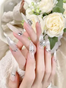 Close-up of nude cat eye stiletto press-on nails with sparkling rhinestones and silver accents