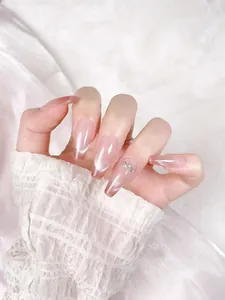 Detail of pink cat-eye press-on nails with glitter ombre and rhinestone accents