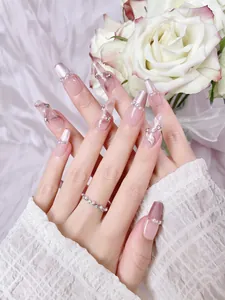 Detail of pink marble press-on nails with pearl edging and crystal rhinestone accents