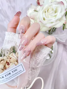 Detail of pink cat-eye press-on nails with 3D ribbons, pearls and rhinestones decoration