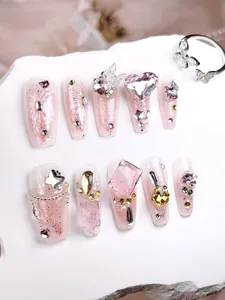 Macro view of long ballerina press-on nails with 3D crystal butterflies and pink zircons