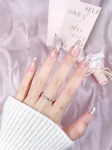 Detail of pink gradient press-on nails with pearl accents and gold chain embellishments