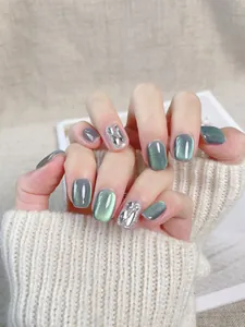 Macro di unghie a occhio di gatto verde scuro con glitter argento e dettagli in strass