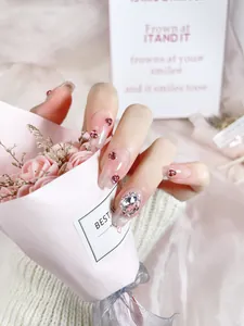 Macro detail of long coffin press-on nails with pink gradient and 3D heart rhinestones