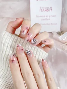 Detail of pink gradient press-on nails with silver glitter and heart-shaped rhinestones