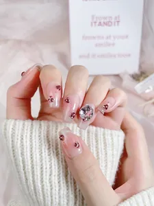Detail of pink gradient press-on nails with glitter and large multi-faceted crystal