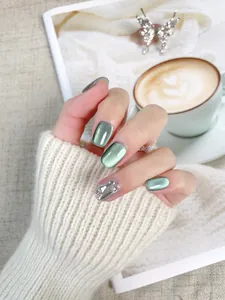 Dettaglio di unghie finte occhio di gatto verde scuro con strass e glitter argento
