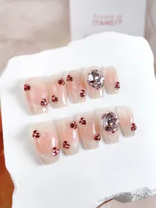 Detail of glitter gradient press-on nails with red rhinestones and large crystals