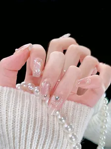 Close-up of handmade press-on nails with pink cat-eye effect and shell texture decor