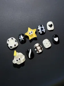 Detalle de 10 uñas postizas hechas a mano para niños con estrellas y patrones de corazón