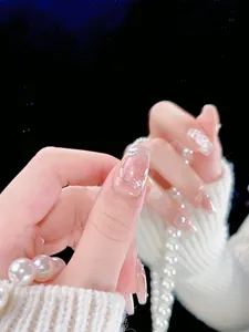 Macro detail of nude cat-eye press-on nails with sparkling rhinestones and pearls