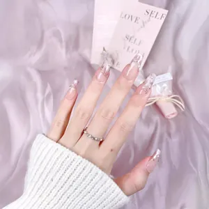 Handmade pink cat-eye press-on nails with pearl accents on a pink silk background