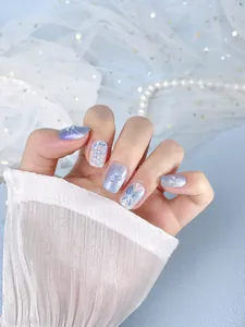 Detail of blue cat-eye press-on nails with 3D butterfly, silver glitter and pearls