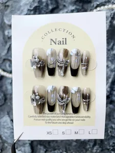 Detail of luxury handmade French press-on nails with rhinestones, pearls and metal chains