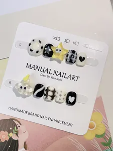 Detalle de uñas postizas hechas a mano para niños con diseños de estrellas y cuadros