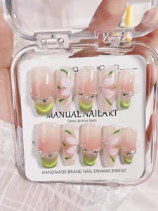 Detail of handmade green cat-eye press-on nails with floral accents and pearls