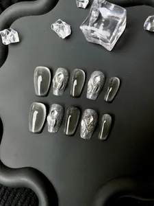 Gros plan d'ongles cat eye gris foncé avec strass 3D sur un plateau noir mat