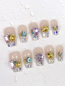 Detailed view of handmade long press-on nails with sparkling rhinestones and heart gems