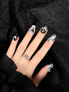 Dettaglio di unghie finte artigianali con farfalle d'argento, croci e strass lucidi