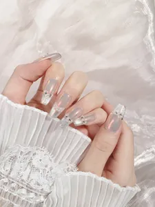 Macro detail of long coffin press-on nails with aurora finish, pearls and crystals