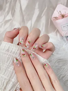 Makro-Detail von Kirsch-Kunstnägeln mit Silberglitzer und Strass auf weißem Stoffhintergrund