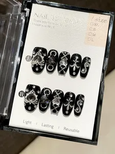 Macro shot of 10 gothic black press-on nails with silver heart and cross charms
