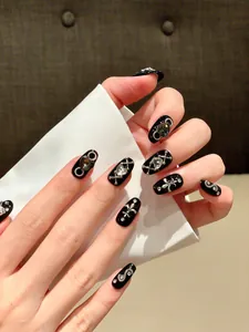 Detail view of black gothic press-on nails with silver cross and rhinestone decorations