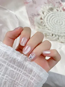 Detail of short pink cat-eye press-on nails with 3D butterfly and rhinestone accents
