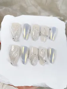 Close-up of almond press-on nails with pearl accents and silver gradient on stone base