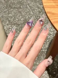 Detailed view of long coffin press-on nails with purple 3D heart rhinestones and silver crosses