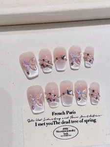 Detail of pink cat eye press-on nails with 3D butterfly charms and rhinestone accents
