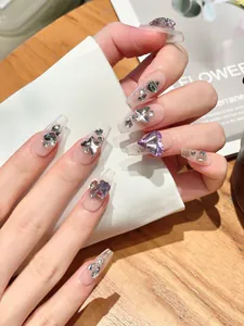 Close-up of long coffin fake nails with silver butterflies and purple heart rhinestones