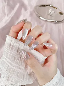 Détail de faux ongles œil-de-chat argentés avec papillons 3D sur forme amande