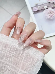 Detail of pink cat-eye press-on nails with butterfly pattern and pearl rhinestones