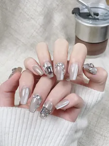 Détail des faux ongles œil de chat gris argenté avec strass brillants et cristaux