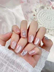 Macro detail of nude pink cat-eye press-on nails with 3D crystal butterfly accents