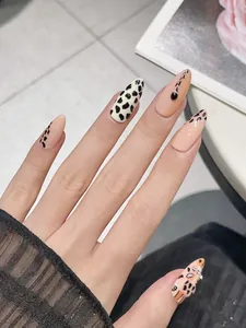 Close-up of almond-shaped press-on nails with hand-painted leopard print and 3D gems