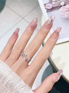 Macro detail of pink gradient press-on nails with 3D butterfly, pearls, and cat-eye finish