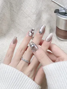 Détail de faux ongles œil de chat mocha avec diamants carrés et cristaux scintillants