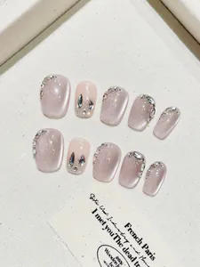 Detail of pink cat eye handmade press-on nails with sparkling rhinestones and glitter