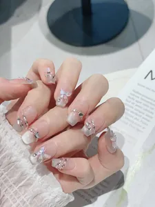 Detail of pink cat eye press-on nails with 3D butterfly, rhinestones and pearls charms