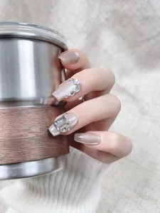 Détails d'ongles champagne doré œil de chat décorés de strass brillants et élégants