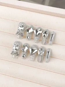 Detail of luxury handmade silver glitter press-on nails with rhinestones and pearls