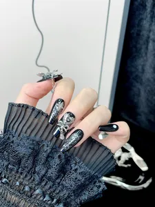 Detail of Gothic Y2K press-on nails with silver glitter, metal butterflies and 3D heart charms