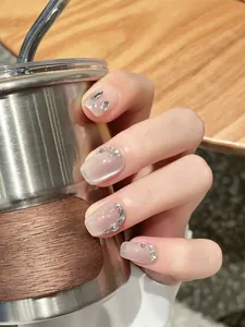Close-up of handmade cat-eye press-on nails with silver glitter and rhinestone accents