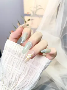 Detail of long coffin press-on nails with green cat-eye effect and 3D floral accents